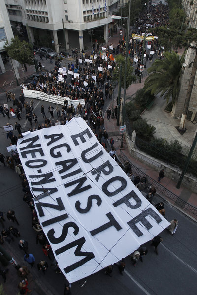 Protesters hold a giant banner during a  silent march through the streets of Athens in protest against racism and neo-nazism, Saturday Dec. 15 2012. A few hundred people marched from Greece’s parliament to the Acropolis to protest against  Golden Dawn, a formerly marginal anti-immigrant movement with a neo-Nazi past, that won nearly 7 percent of the vote in national elections last June to enter Parliament for the first time, capitalizing on the economic crisis, soaring unemployment, rising crime and peoples’ fears from an unchecked immigration wave. (AP Photo/Kostas Tsironis)